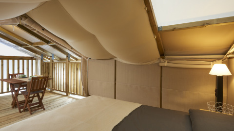 Interieur van de Airlodge 2.0 bij Vacanze Glamping Boutique Italië, met bed, lamp en houten eethoek.