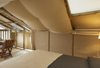 Interieur van de Airlodge 2.0 bij Vacanze Glamping Boutique Italië, met bed, lamp en houten eethoek.