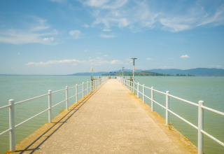 View from a pier at Trasimeno Glamping Resort in Umbria, Italy, overlooking the lake and distant hills.