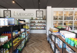 Interno del negozio 'Il Mercato' al Lago Idro Glamping Boutique con scaffali pieni di prodotti assortiti.