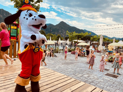 Des enfants jouent près d’une mascotte chien au parc Lago Idro Glamping Boutique en Lombardie, Italie.
