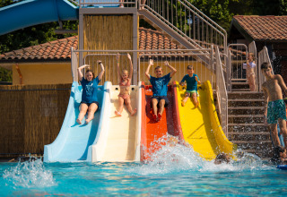 Bambini e adulti si divertono sugli scivoli colorati nella piscina del Trasimeno Glamping Resort in Umbria.
