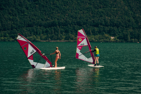 Due persone fanno windsurf sul Lago d’Idro circondato da montagne, punto forte di Lago Idro Glamping Boutique.