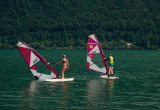 Twee mensen windsurfen op het Idromeer omringd door bergen, bij Lago Idro Glamping Boutique in Italië.