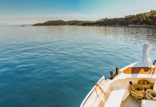 Vista da una barca verso la costa tranquilla vicino a Cadaqués, Girona, Catalogna, Spagna, sotto cielo sereno.