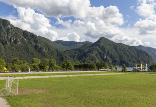 Voetbalveld met groene bergen en een meer op de achtergrond bij Lago Idro Glamping Boutique in Lombardije, Italië.