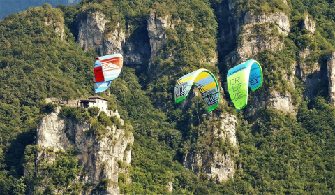 Kitesurfer sorvolano una scogliera rocciosa con casa vicino al Lago Idro Glamping Boutique in Lombardia, Italia.