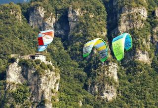 Kitesurfer sorvolano una scogliera rocciosa con casa vicino al Lago Idro Glamping Boutique in Lombardia, Italia.