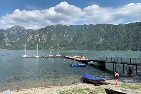 Jetée et bateaux au Lago Idro Glamping Boutique en Lombardie, Italie, avec montagnes verdoyantes en arrière-plan.