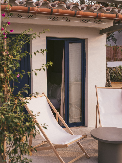 Terrasse extérieure au Wecamp Cadaqués en Catalogne, avec deux chaises longues et une petite table grise.