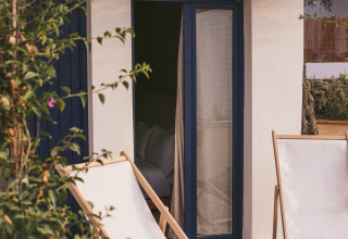 Terrasse extérieure au Wecamp Cadaqués en Catalogne, avec deux chaises longues et une petite table grise.