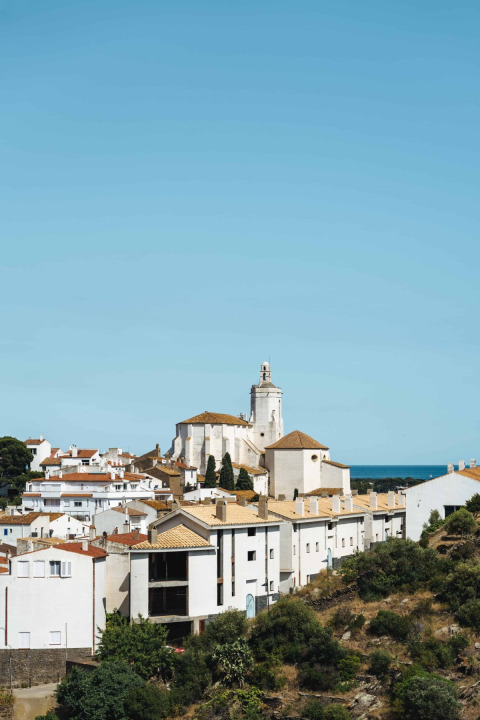 Blick auf die weißen Häuser und die Kirche von Cadaqués in Girona unter blauem Himmel in Katalonien, Spanien.