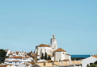 Vista de los edificios blancos y la iglesia de Cadaqués, Girona, bajo un cielo azul claro en Cataluña, España.