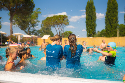 Bambini e adulti giocano e schizzano nell'acqua della piscina al Trasimeno Glamping Resort in Umbria, Italia.