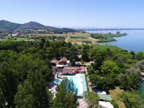 Vista aerea del Trasimeno Glamping Resort in Umbria, Italia, circondato da alberi e con vista sul lago.