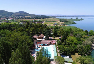 Vista aerea del Trasimeno Glamping Resort in Umbria, Italia, circondato da alberi e con vista sul lago.