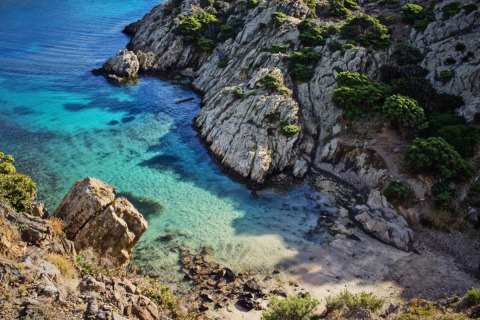 Vista panoramica su una cala nascosta con acqua turchese, scogli e verde vicino a L'Escala, Catalogna, Spagna.