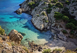Vista panorámica de una cala de aguas turquesas, acantilados rocosos y vegetación cerca de L'Escala, Cataluña.