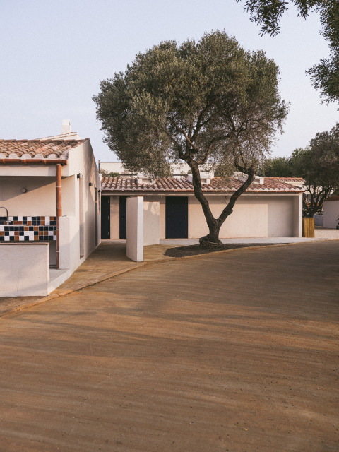 Vakantiewoning bij Wecamp Cadaqués in Catalonië, Spanje, met pannendak en een grote boom ervoor.