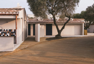 A holiday home at Wecamp Cadaqués in Catalonia, Spain, with tiled roof and a large tree in front.