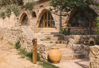 Bâtiment en pierre avec fenêtres en arche entouré de verdure à Wecamp Cala Montgó, en Catalogne, Espagne.