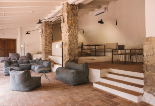 Modern lounge at Wecamp Cala Montgó holiday park with bean bags, stone columns, and tiered seating.
