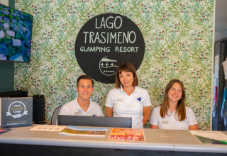 Lo staff della reception del Trasimeno Glamping Resort in Umbria, Italia, sorride accogliendo gli ospiti.
