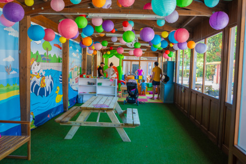 Area giochi interna colorata con lanterne di carta e tavolo da picnic al Trasimeno Glamping Resort.