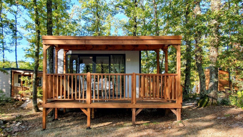 Vooraanzicht van Cube Suite-lodge met houten terras, midden in het bos en omgeven door groene bomen.
