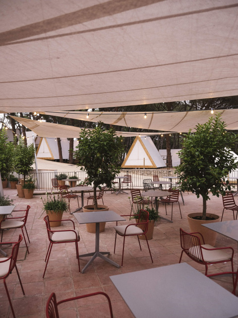Terrasse de café extérieure avec tables, chaises et plantes au Wecamp Cala Montgó, parc de vacances en Catalogne, Espagne.
