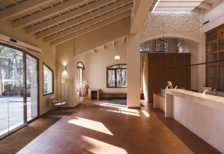 Lys og moderne reception med store vinduer, trædetaljer og minimalistisk indretning på Wecamp Cala Montgó.