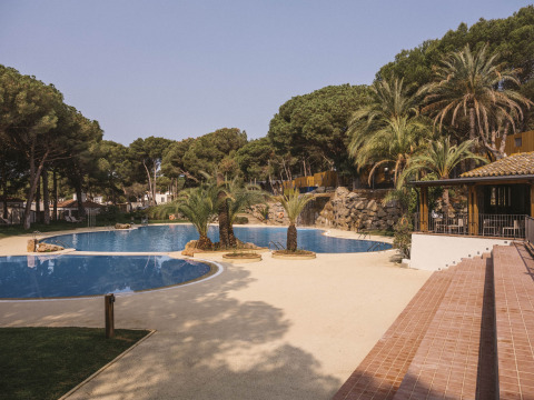 Parque vacacional Wecamp Cala Montgó en Cataluña, España, con piscina, palmeras y ambiente tranquilo.