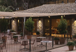 Terraza exterior del parque vacacional Wecamp Cala Montgó en Cataluña, con luces y vegetación en macetas.