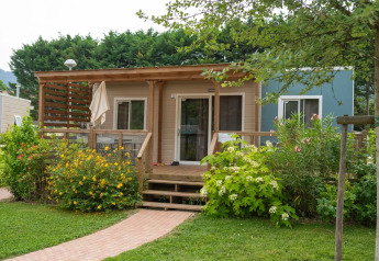 Vista frontale di Cottage Next XL Superior 6 pers. con terrazza, circondato da giardino e fiori colorati.