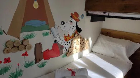 Chambre de lodge avec lits superposés et fresque murale d’un dalmatien en chapeau et pantalon rouges.