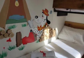 Camera di un lodge con letto a castello e murale di un dalmata con cappello e pantaloni rossi.