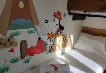 Habitación de una cabaña con litera y mural de un dálmata usando sombrero rojo y pantalones rojos.