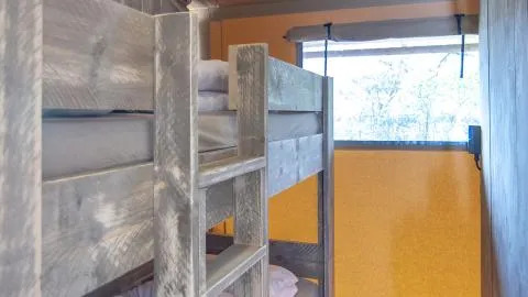 Interieur van Safari Tenten bij Chianti Glamping Resort in Italië met stapelbedden en raam.