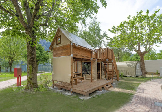 Foto de una tienda safari Air Dreamer con terraza de madera y azotea, rodeada de naturaleza verde.