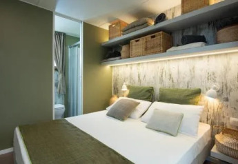 Dormitorio de Cottage Next L Evo en Chianti Glamping Resort, Italia, decoración verde, estanterías sobre la cama.