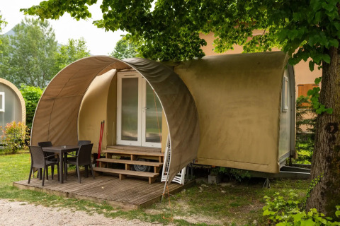 Coco Suite pod met overdekt houten terras, tuinmeubilair en omgeven door groene natuur.