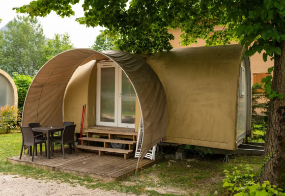 Coco Suite pod met overdekt houten terras, tuinmeubilair en omgeven door groene natuur.