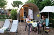 Zwei Personen entspannen vor einem Coco Couple Safari-Zelt im Chianti Glamping Resort in Italien und essen im Freien.
