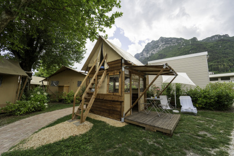 Airstay safaritent met houten terras, buitenmeubels en zicht op de bergen, omringd door groen.