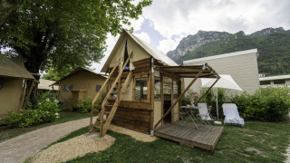 Tenda safari Airstay con veranda in legno, arredi da esterno e vista sulle montagne, immersa nel verde.