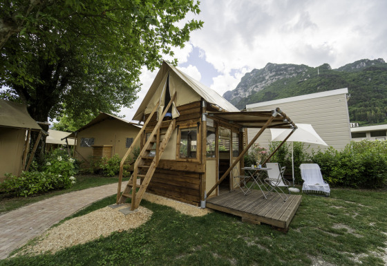 Airstay safaritent met houten terras, buitenmeubels en zicht op de bergen, omringd door groen.