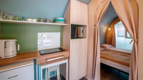Vue intérieure d'une tente safari Coco Suite avec kitchenette et chambre au Chianti Glamping Resort en Italie.