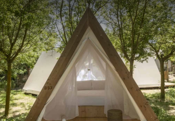 Cabane safari au Wecamp Cala Montgó en Espagne, entourée d’arbres et d’autres tentes blanches en arrière-plan.