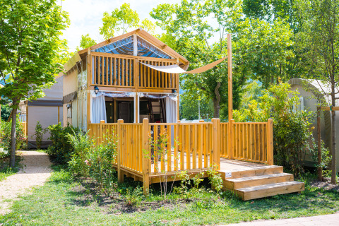 Afbeelding van een gezellige houten lodge bij Air Lodge met zonnig terras, omgeven door groen.