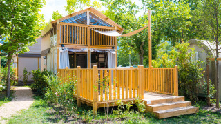 Afbeelding van een gezellige houten lodge bij Air Lodge met zonnig terras, omgeven door groen.
